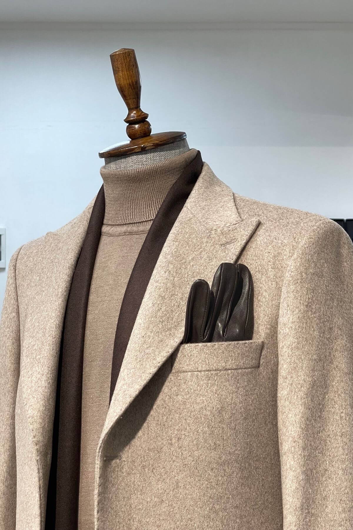 Beige suit jacket on a mannequin with a plain background