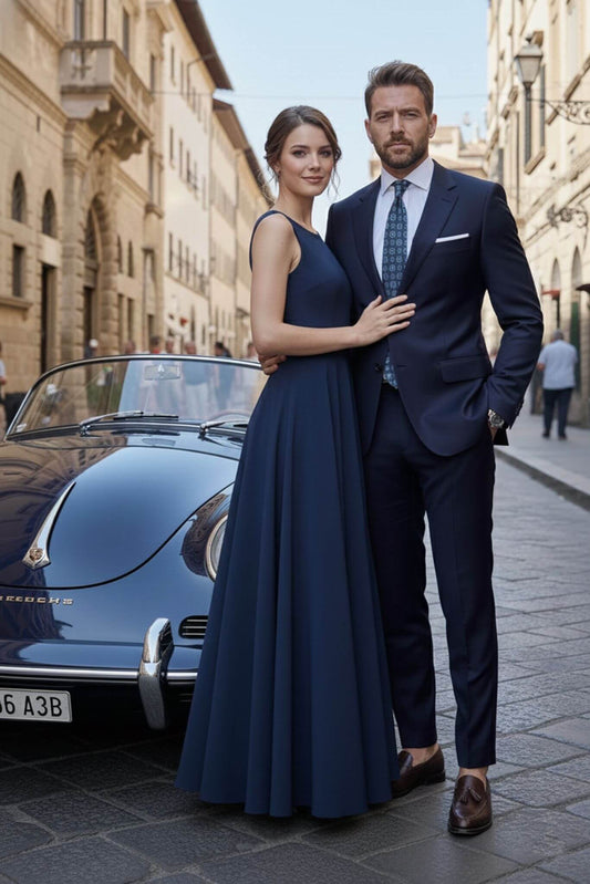 Man and woman in formal attire standing next to a vintage car on a city street.