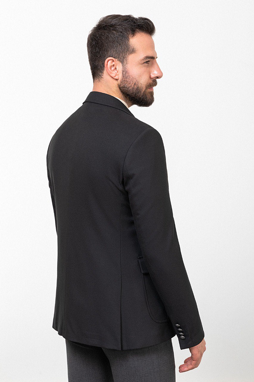 Man wearing a black blazer paired with a beige turtleneck.