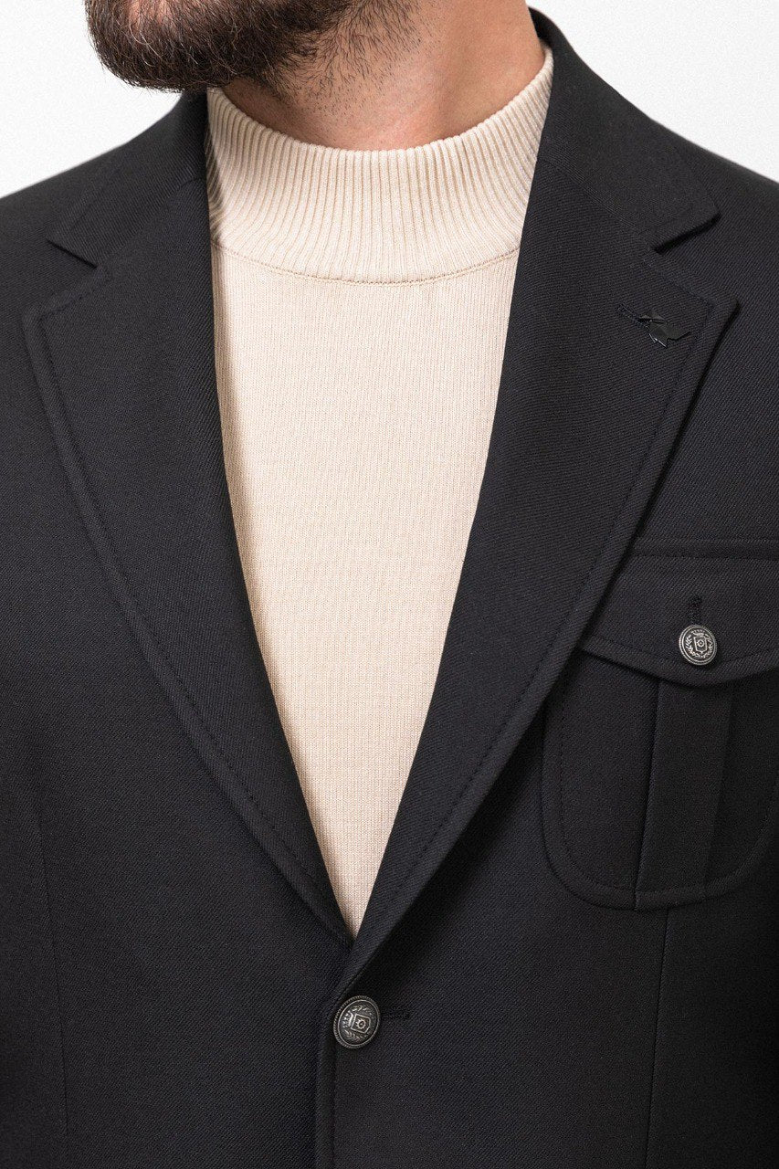 Man wearing a black blazer paired with a beige turtleneck.