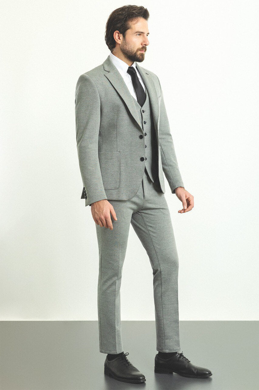 Man wearing a stylish gray 3-piece suit with a black tie and black shoes.