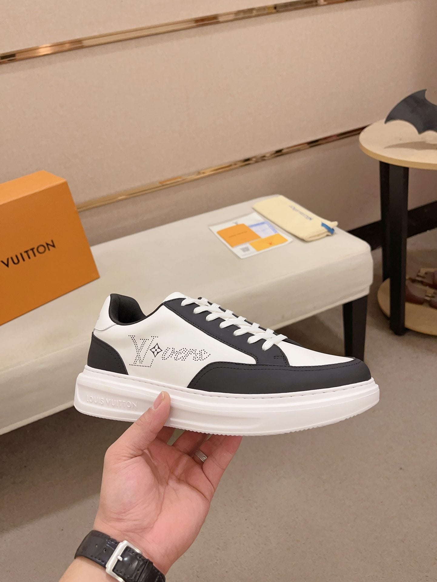 Louis Vuitton black and white contrast low-top sneakers angled side view held in hand