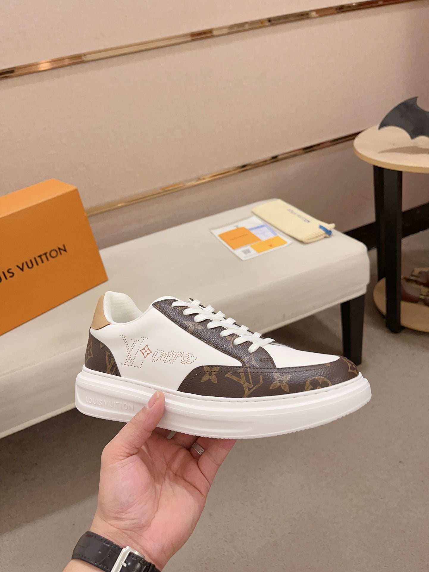 Louis Vuitton brown and white Monogram low-top sneakers angled side view held in hand