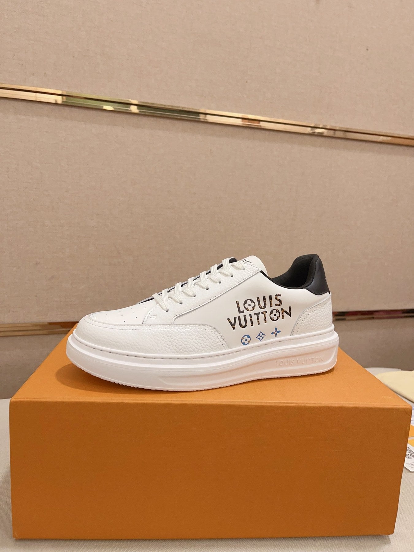 Louis Vuitton white and black logo low-top sneakers side profile on orange box
