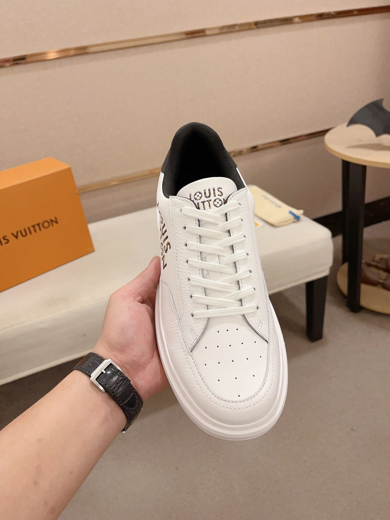 Louis Vuitton white and black logo low-top sneakers top view held upright