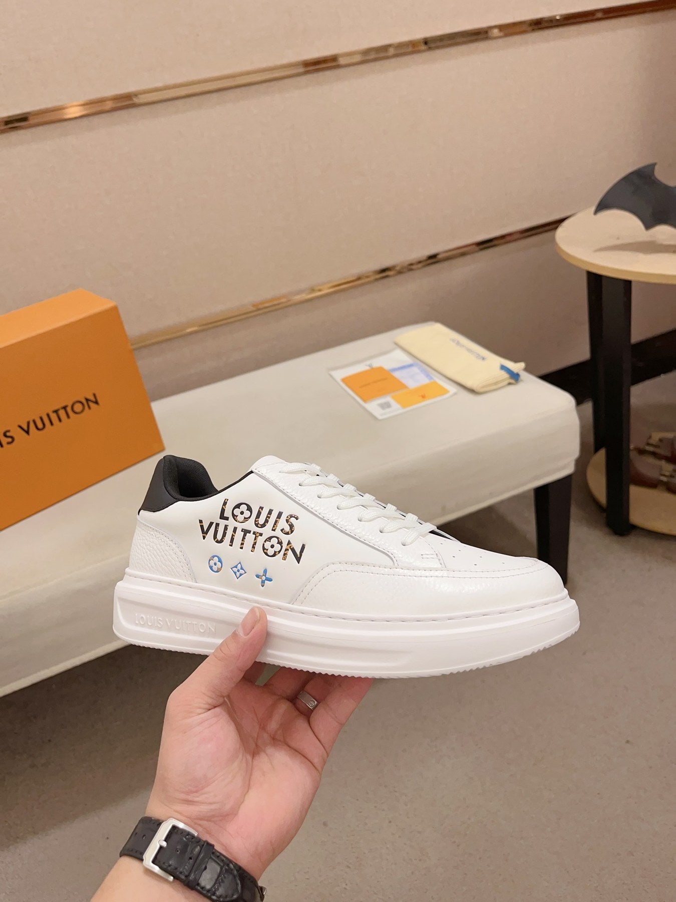 Louis Vuitton white and black logo low-top sneakers angled side view held in hand