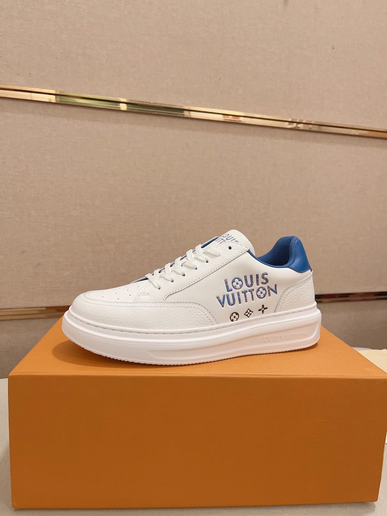 Louis Vuitton white and blue logo low-top sneakers side profile on orange box
