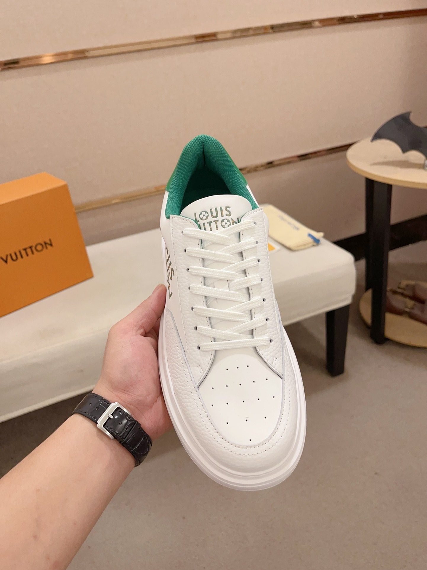 Louis Vuitton white and green logo low-top sneakers top view held upright