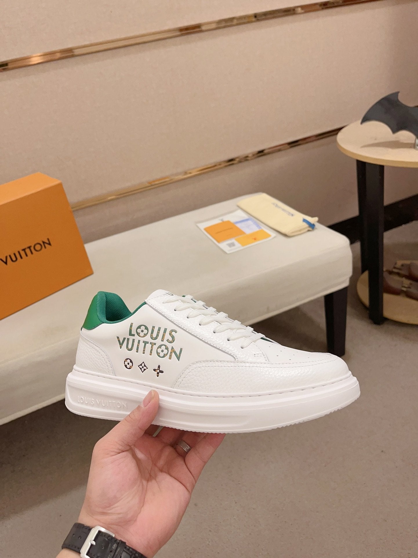 Louis Vuitton white and green logo low-top sneakers angled side view held in hand