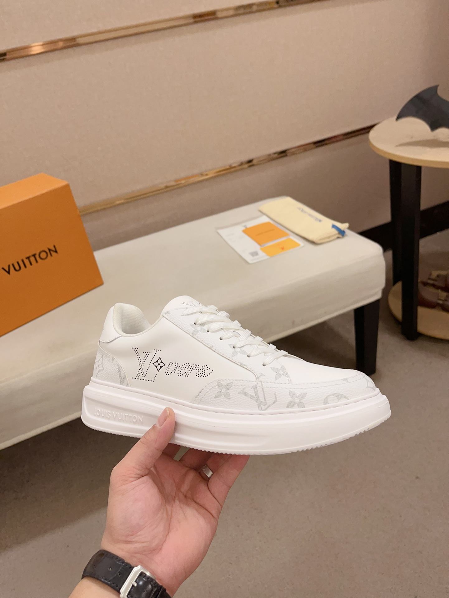 Louis Vuitton white and grey Monogram low-top sneakers angled side view held in hand