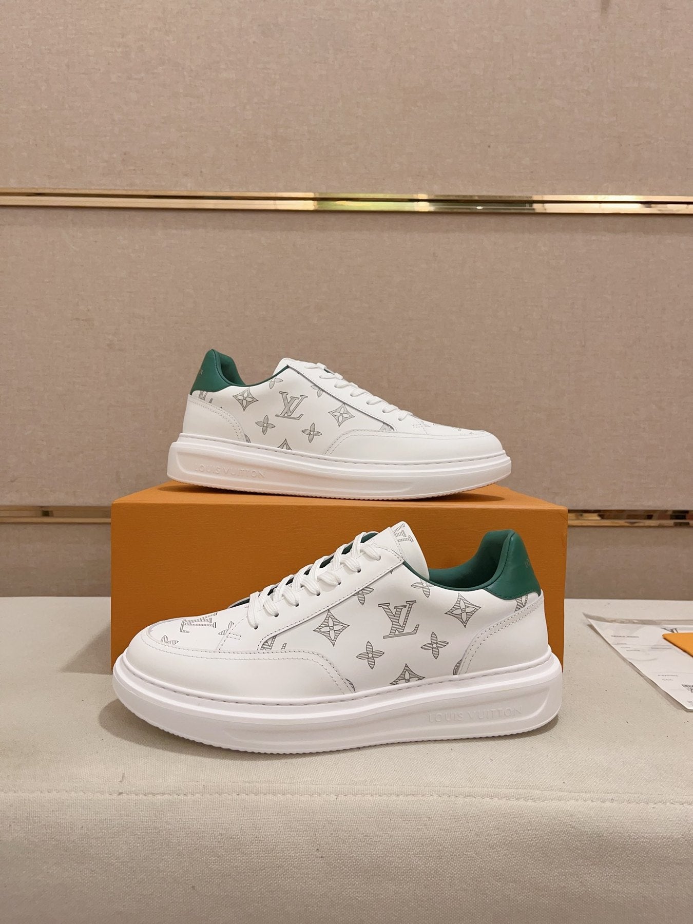Louis Vuitton white monogram green heel low-top sneakers pair displayed with orange box