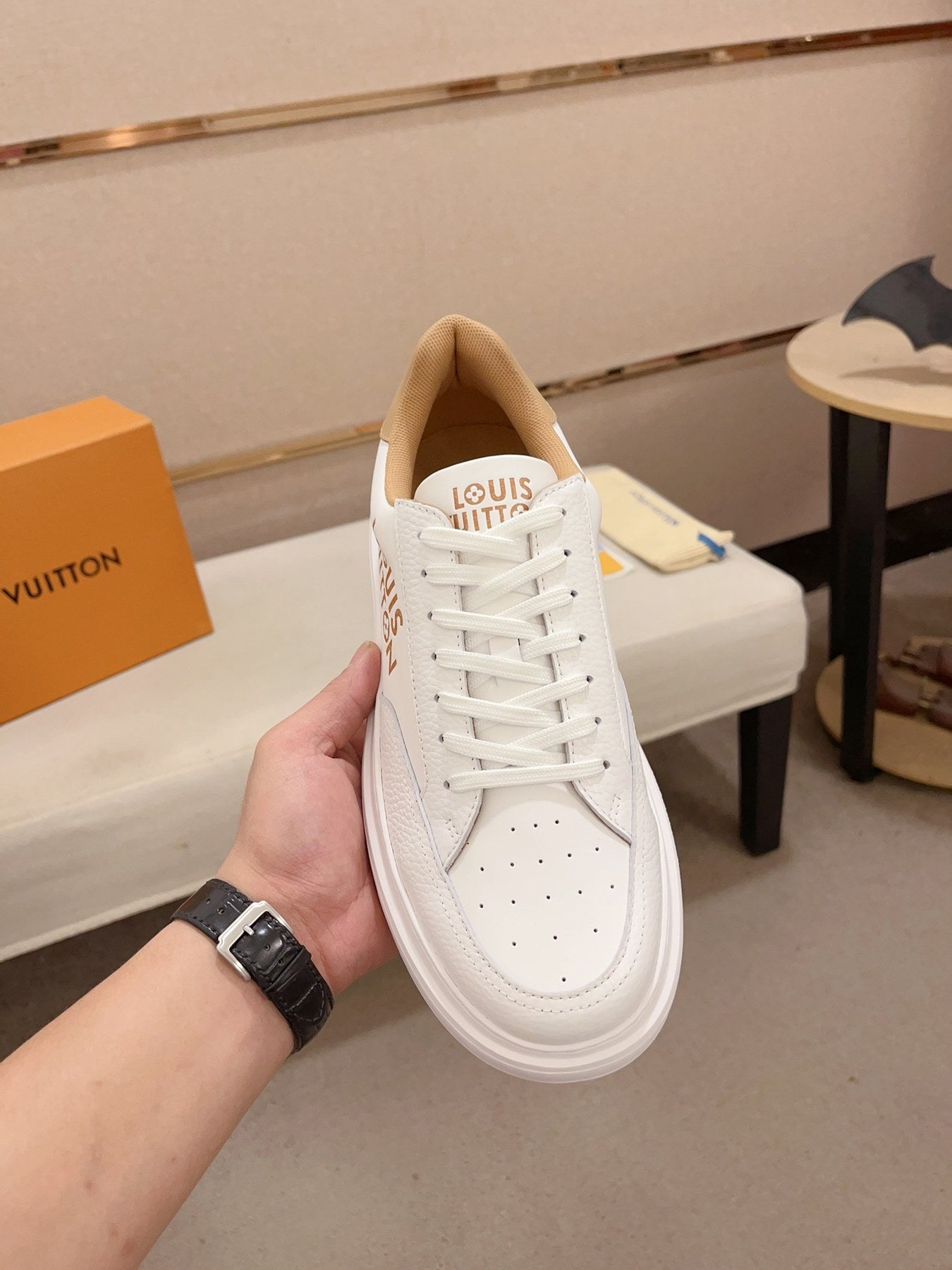 Louis Vuitton white and tan logo low-top sneakers top view held upright