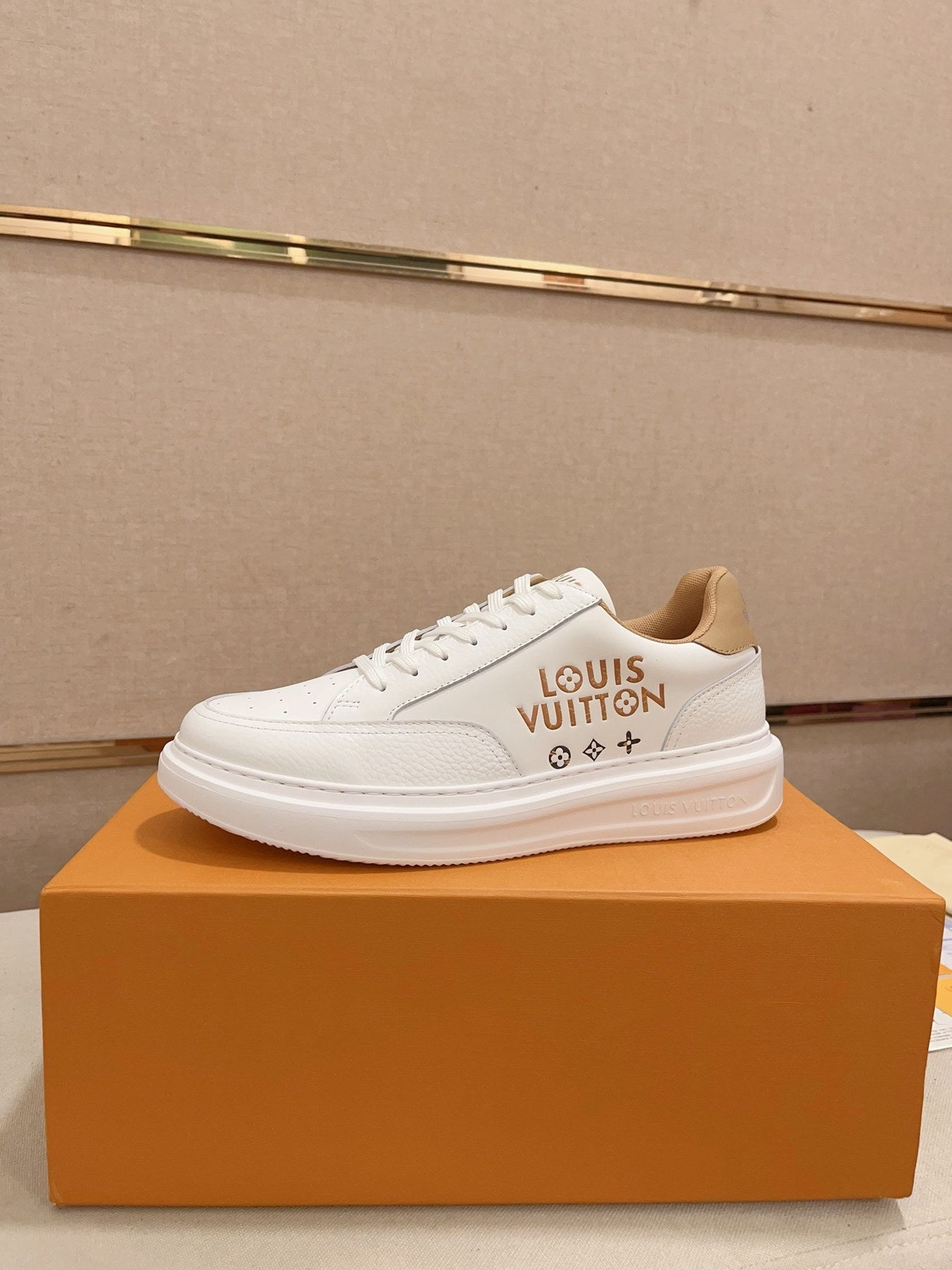 Louis Vuitton white and tan logo low-top sneakers side profile on orange box