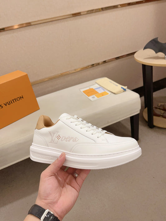 Louis Vuitton white and tan perforated LV low-top sneakers angled side view held in hand