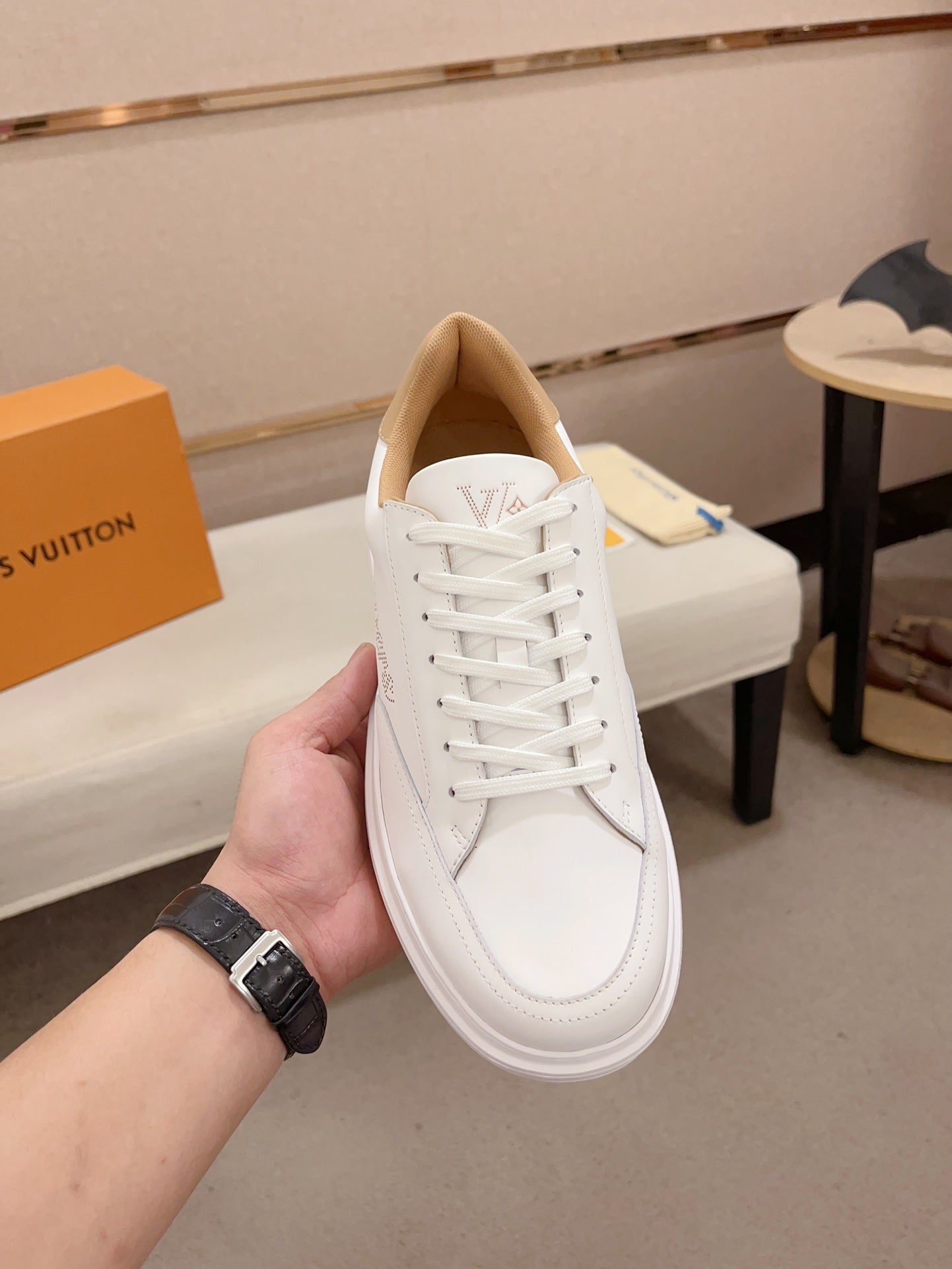 Louis Vuitton white and tan perforated LV low-top sneakers top view held upright