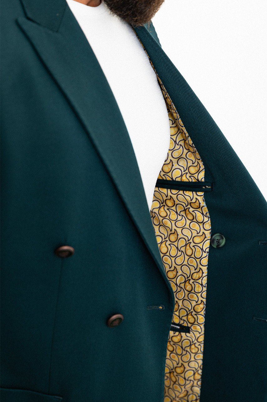 Man wearing a teal double-breasted blazer paired with beige trousers.