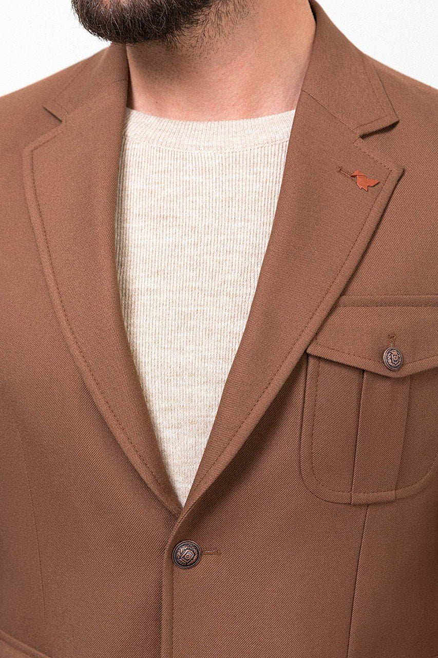 Man wearing a brown tailored blazer paired with a beige sweater and brown trousers, showcasing a smart-casual fall outfit.