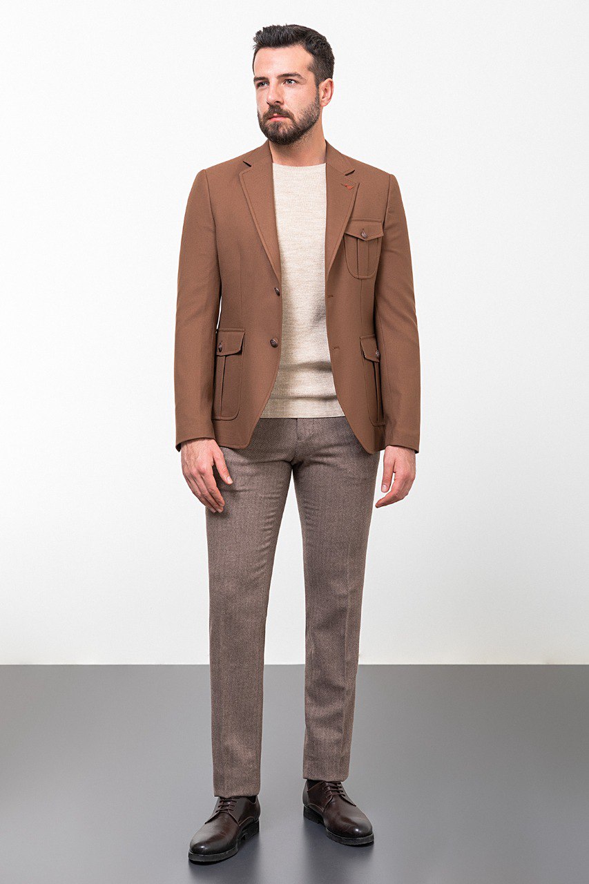 Man wearing a brown tailored blazer paired with a beige sweater and brown trousers, showcasing a smart-casual fall outfit.