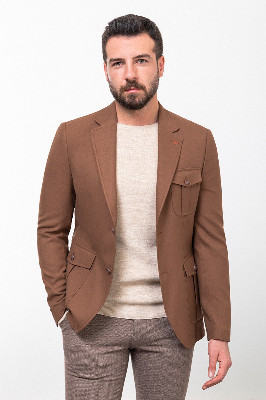 Man wearing a brown tailored blazer paired with a beige sweater and brown trousers, showcasing a smart-casual fall outfit.