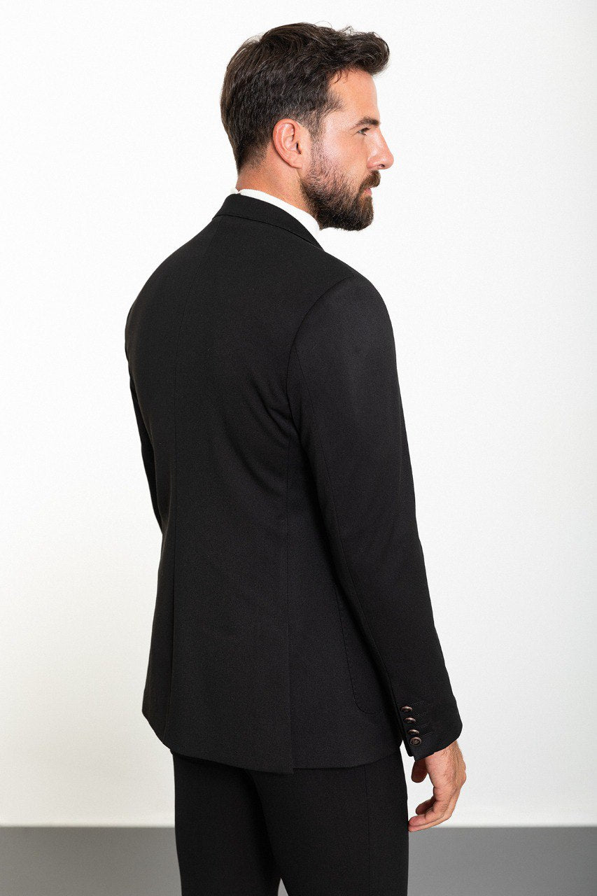 Man wearing a black double-breasted blazer with a white turtleneck, showcasing a modern and sophisticated look for formal or smart-casual occasions.