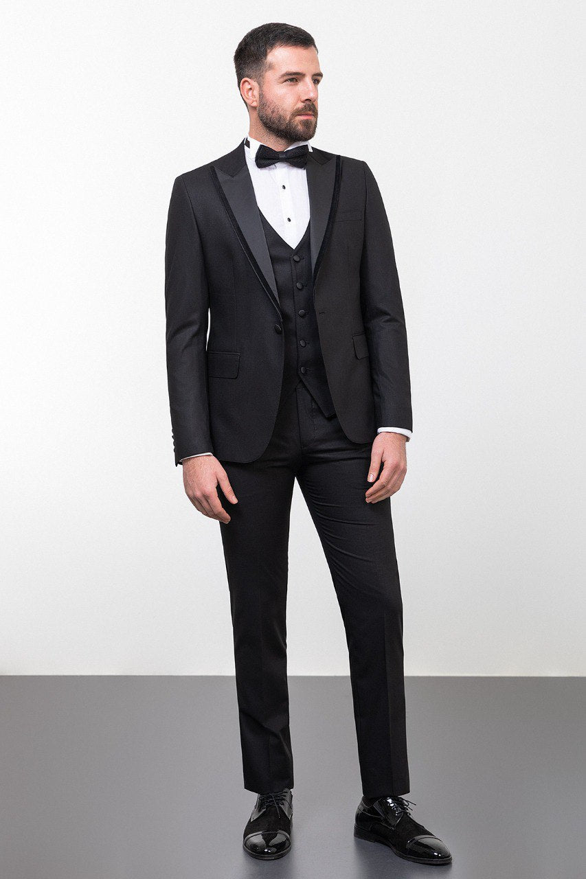 Man wearing an Onyx Elegance Tuxedo with a satin peak lapel, flap pockets, and a slim fit, perfect for black-tie events and weddings.