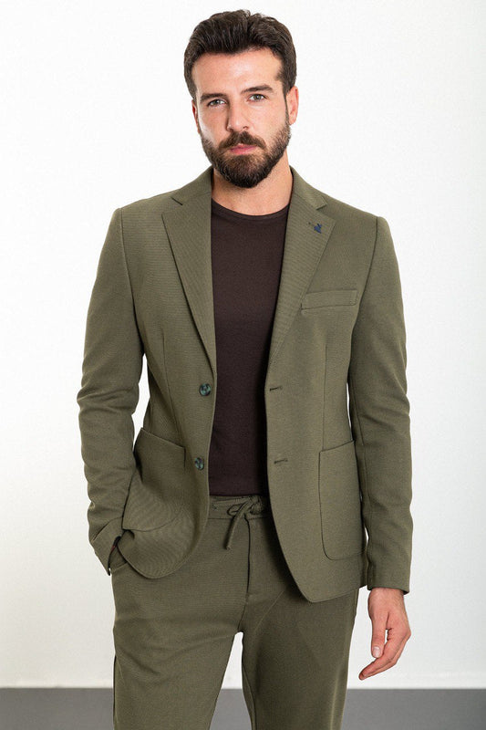 Man wearing an olive green suit with a dark brown T-shirt.