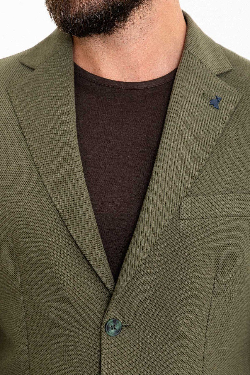 Man wearing an olive green suit with a dark brown T-shirt.