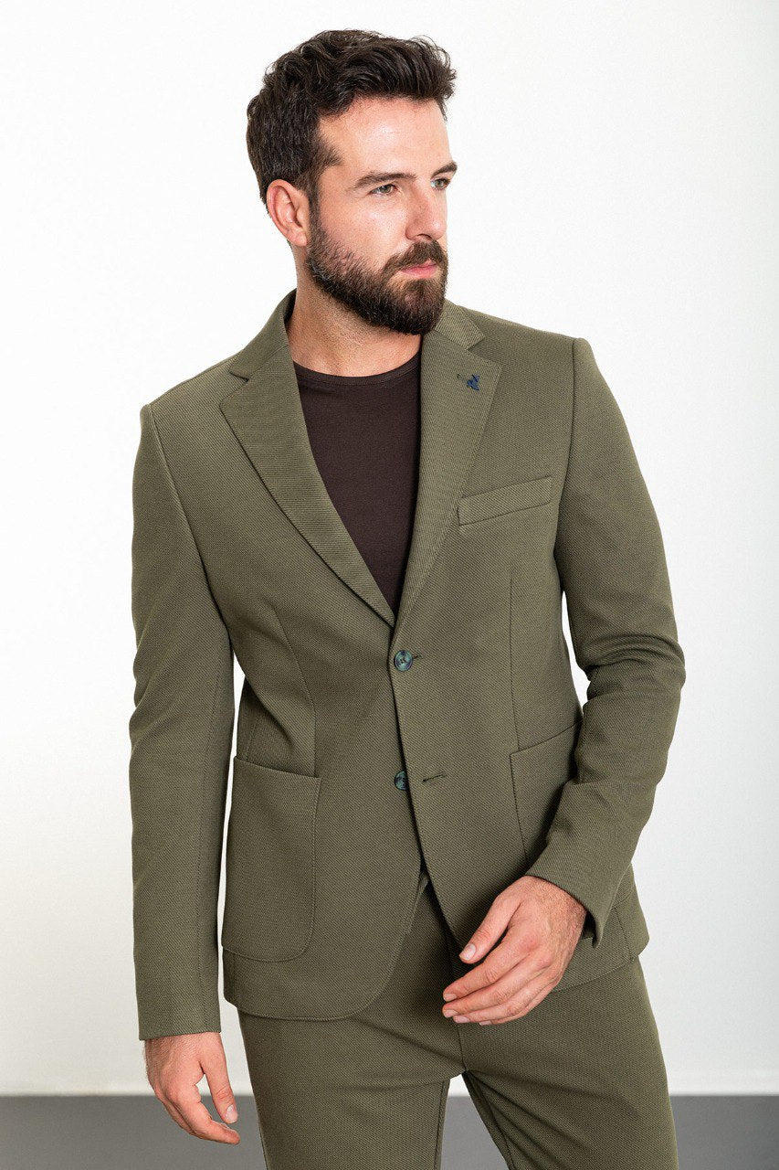 Man wearing an olive green suit with a dark brown shirt.