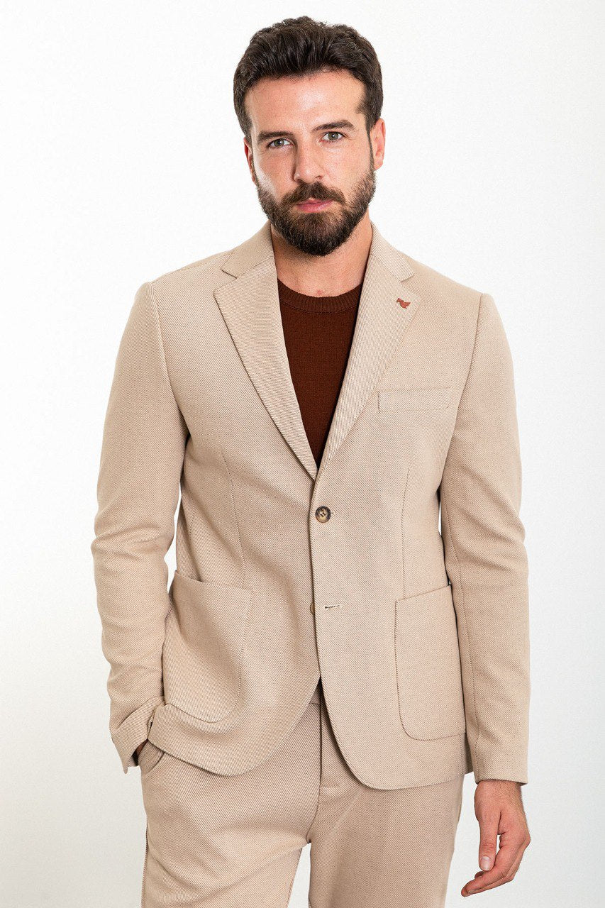 Man in a beige suit wearing a brown t-shirt.