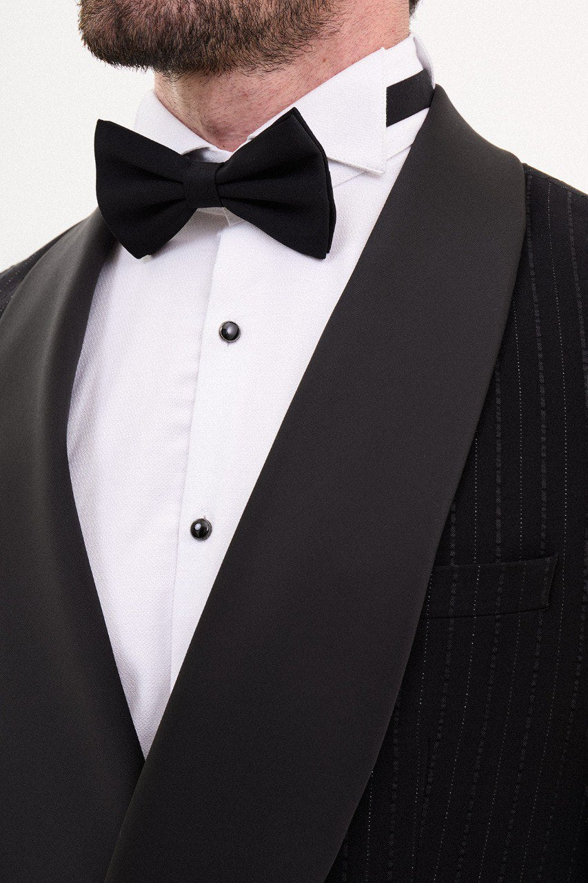 Man wearing a black double-breasted tuxedo with a shawl collar and bow tie.