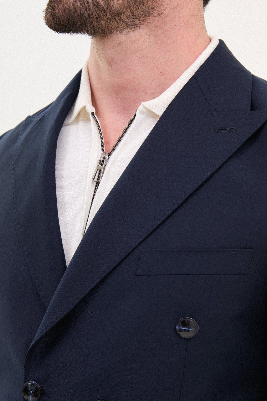 Man wearing a navy blue double-breasted suit with a polo shirt.