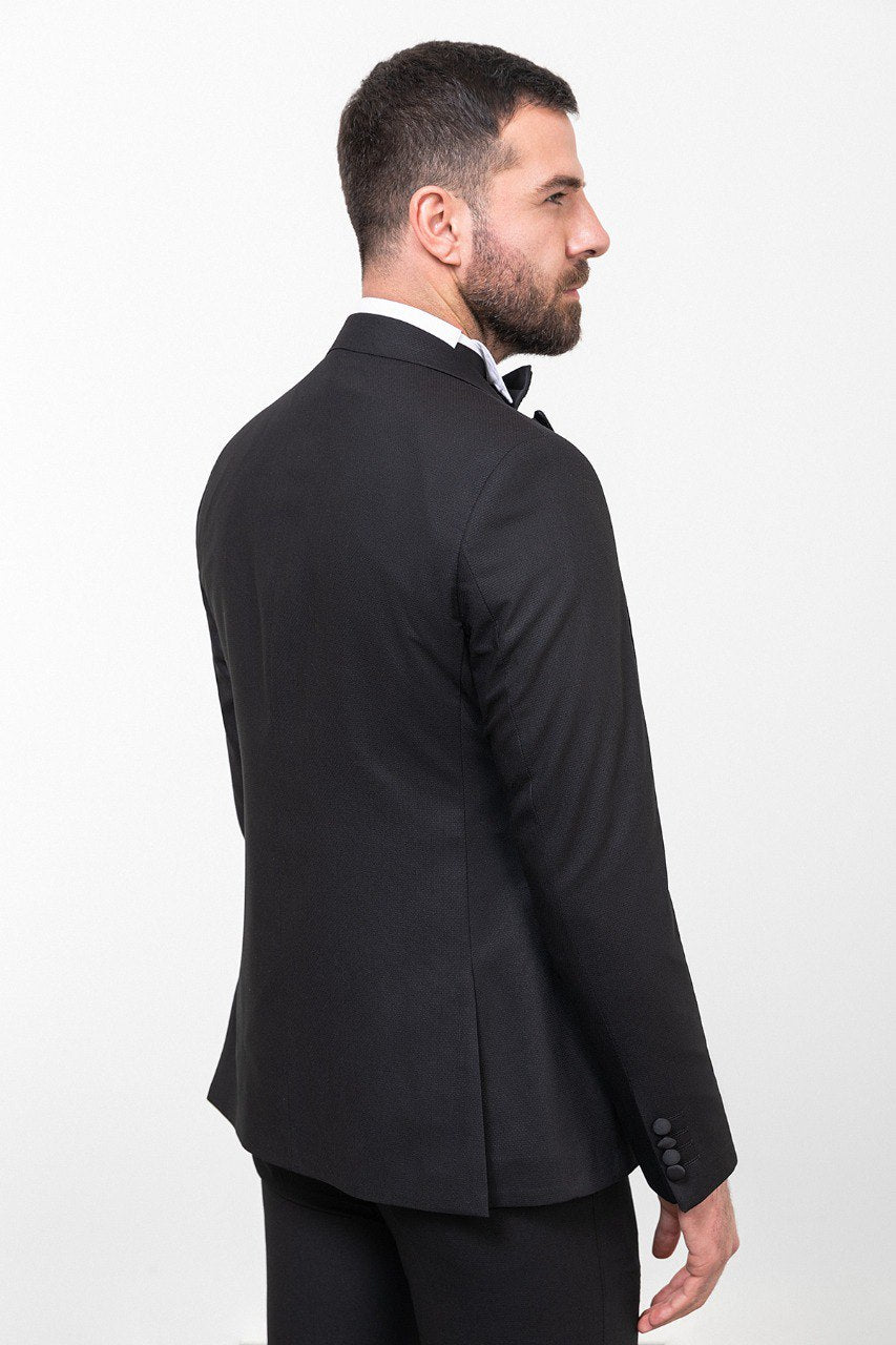 Man wearing an Onyx Elegance Tuxedo with a satin peak lapel, flap pockets, and a slim fit, perfect for black-tie events and weddings.