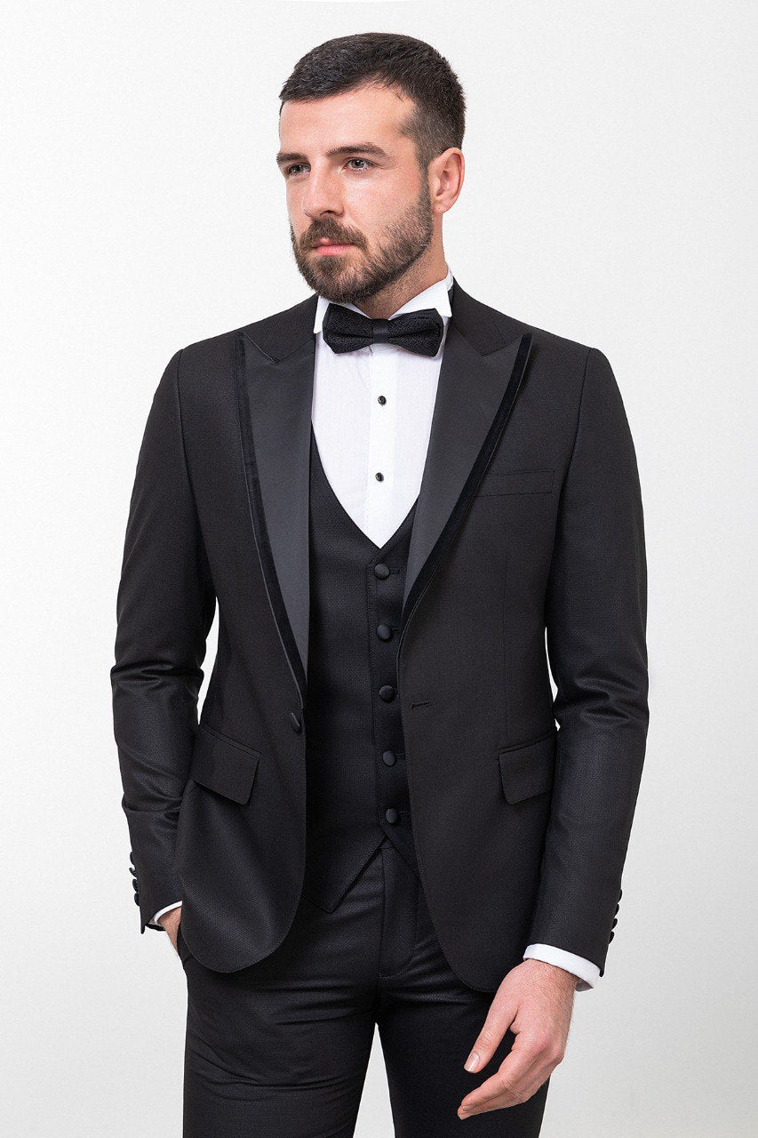 Man wearing an Onyx Elegance Tuxedo with a satin peak lapel, flap pockets, and a slim fit, perfect for black-tie events and weddings.