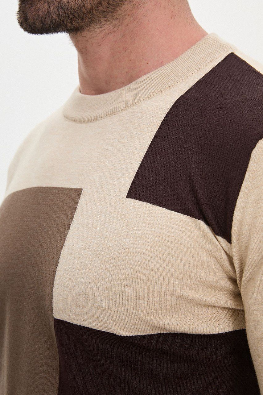 Close-up of the beige sweater's crew neckline and asymmetric colour-block knit