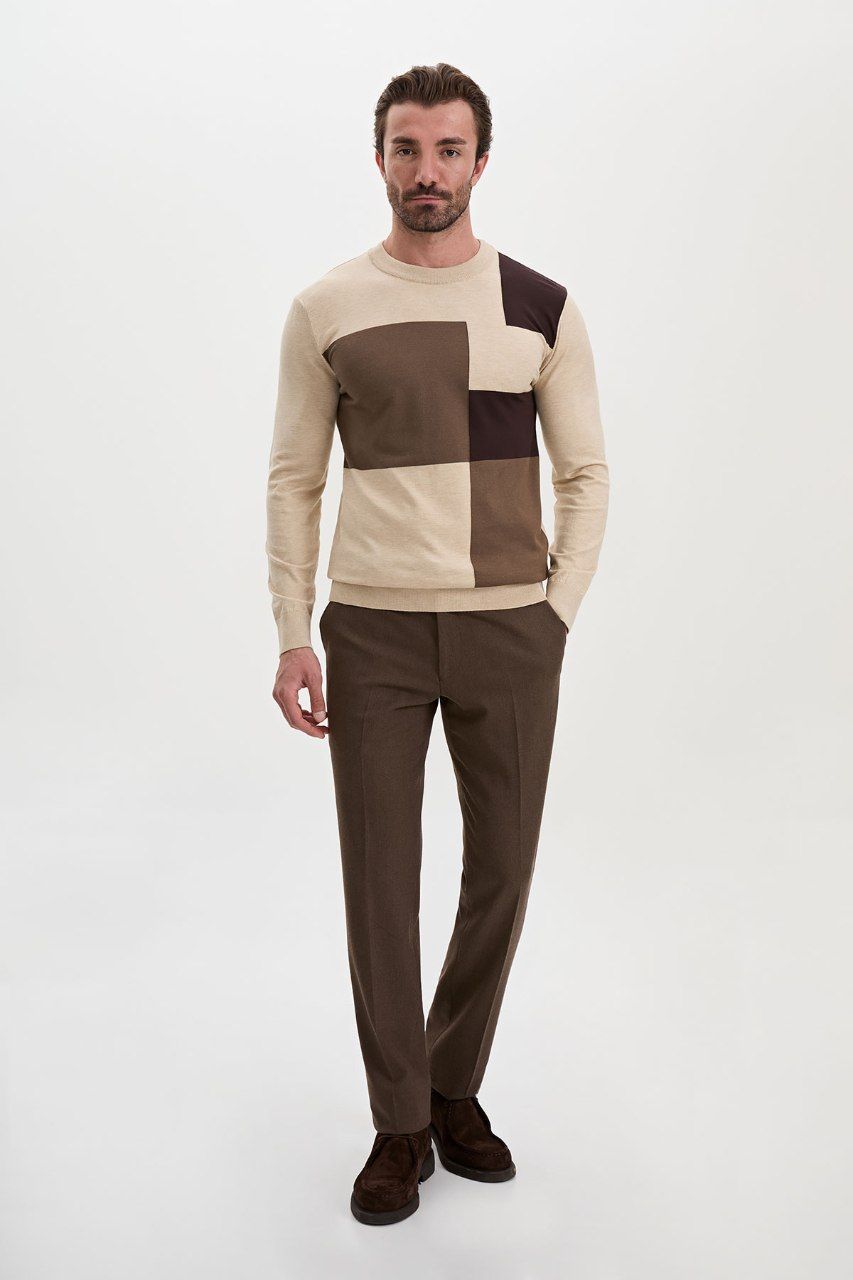 Man wearing a beige colour-block sweater with brown trousers