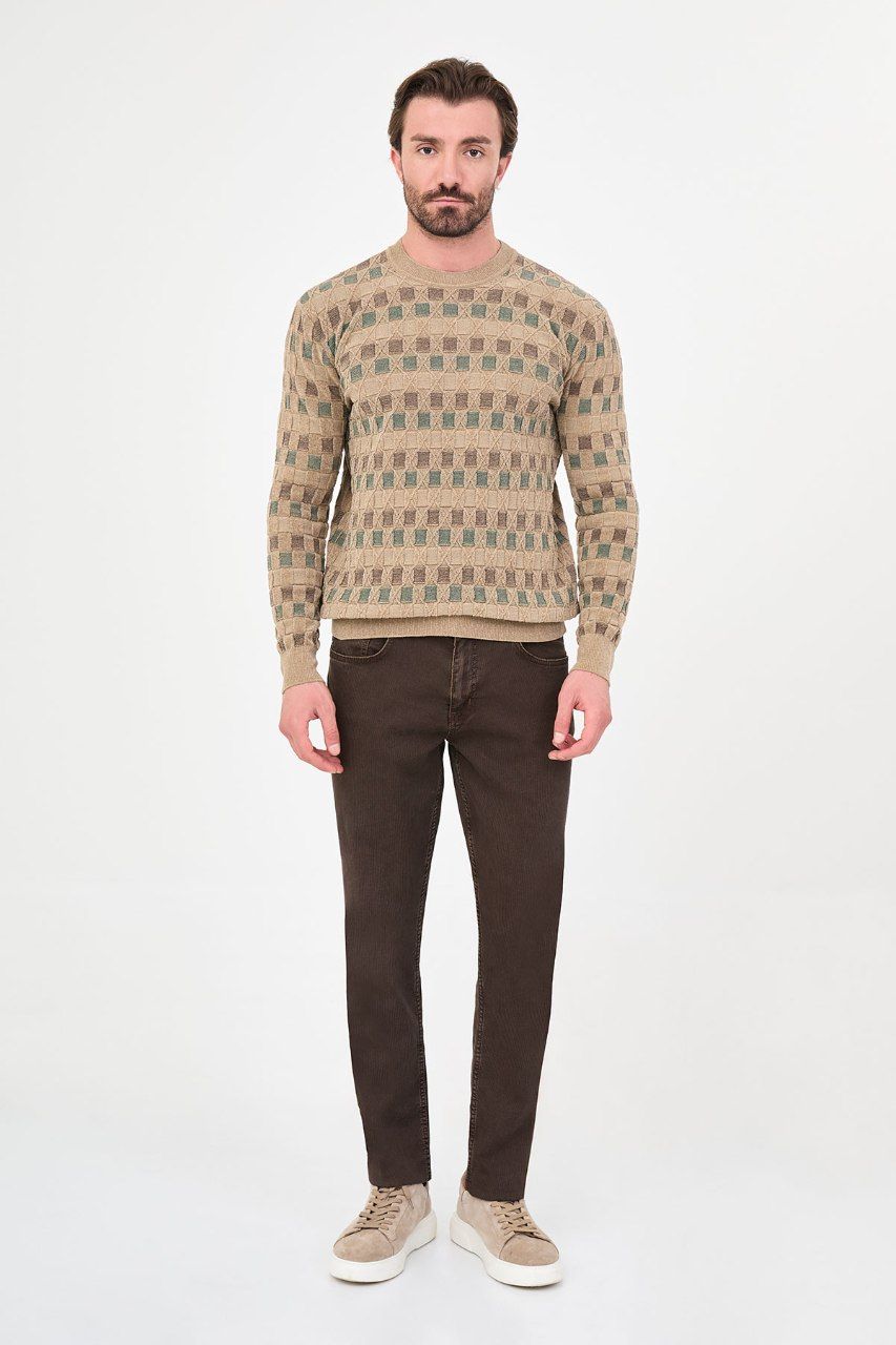 Man wearing a beige geometric crew neck sweater with brown trousers