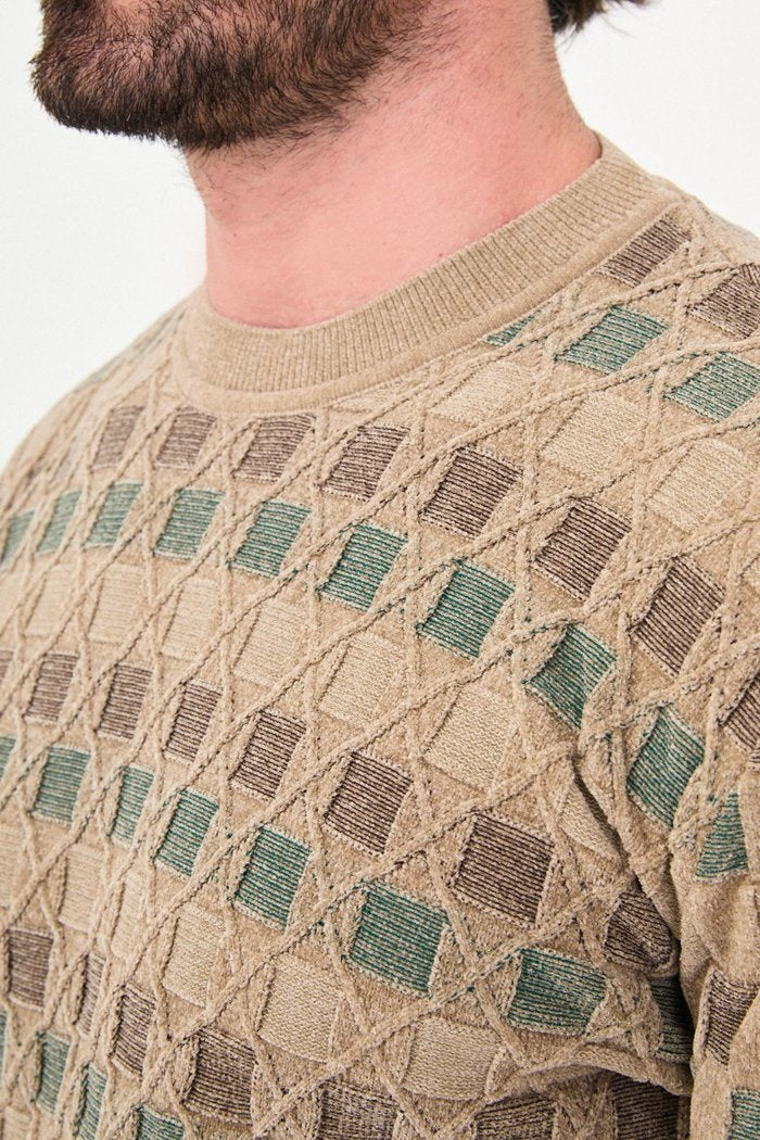 Close-up of square accents and diamond outlines in the beige sweater's knit