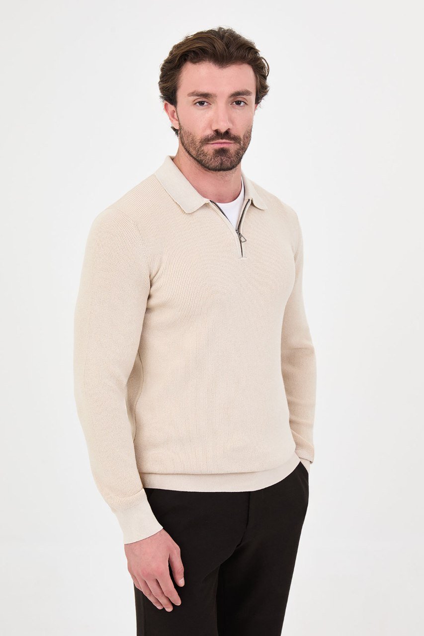 Angled view of a man wearing a beige ribbed quarter-zip polo sweater