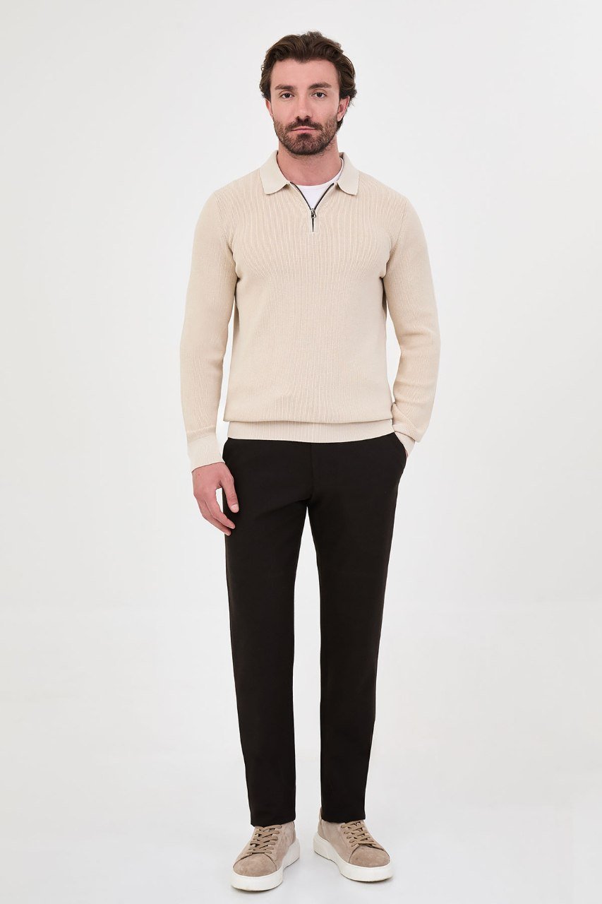 Man wearing a beige ribbed quarter-zip polo sweater with black trousers