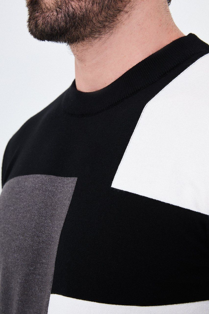 Close-up of the black sweater's crew neckline and asymmetric colour-block knit