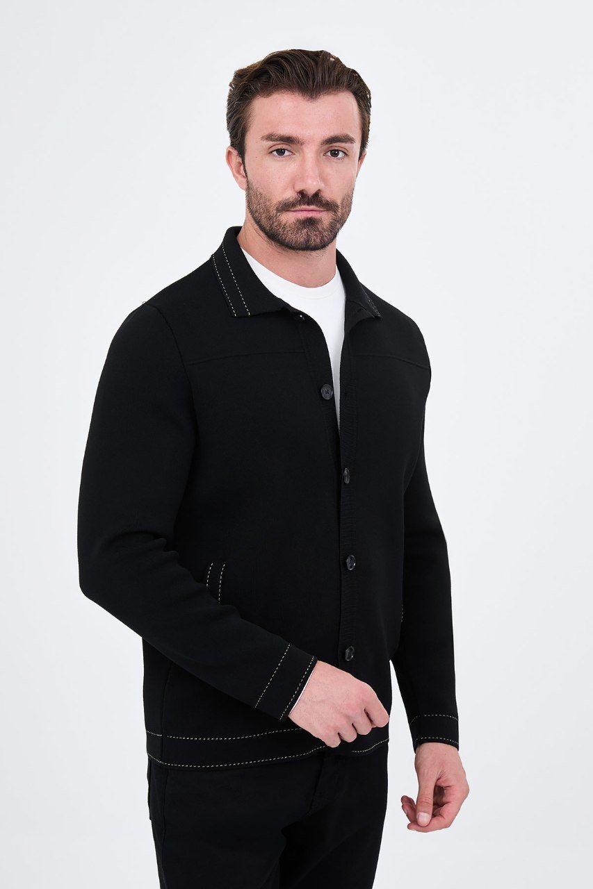 Man wearing a black button-front cardigan with contrast trim, angled view