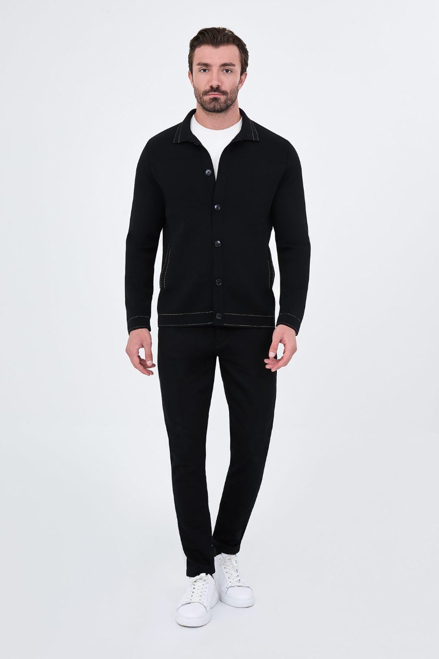 Man wearing a black button-front cardigan with contrast trim, full outfit view