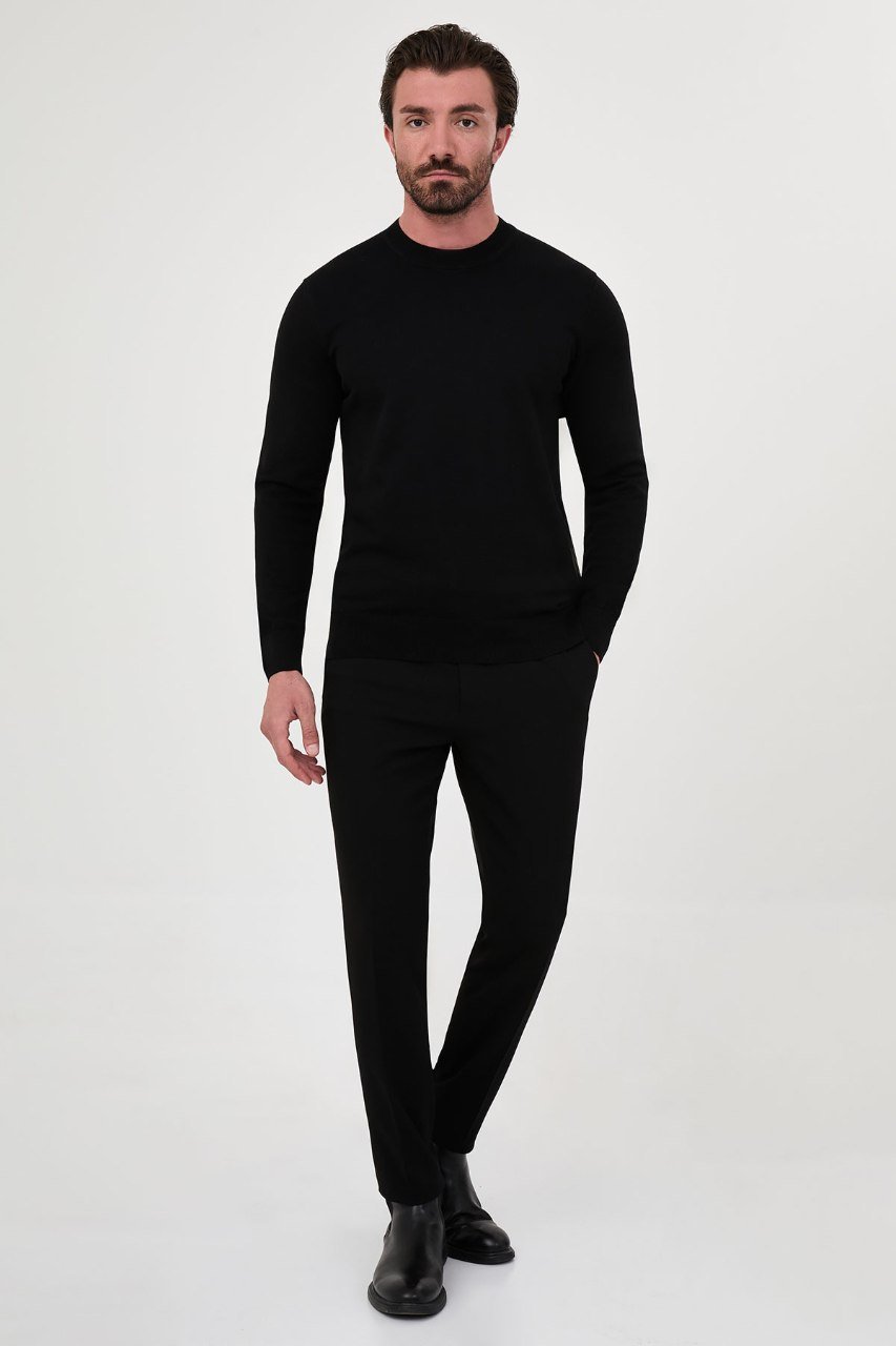 Man wearing a black crew neck sweater with black trousers