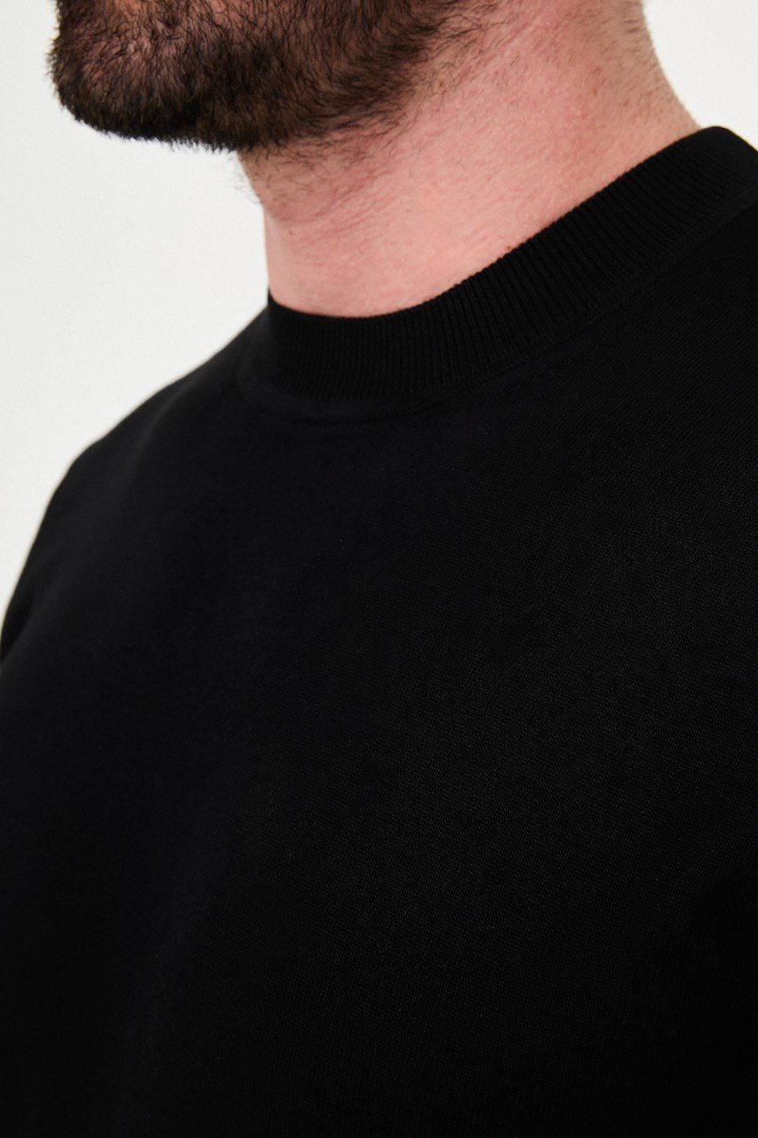 Close-up of the black sweater's crew neckline and fine knit