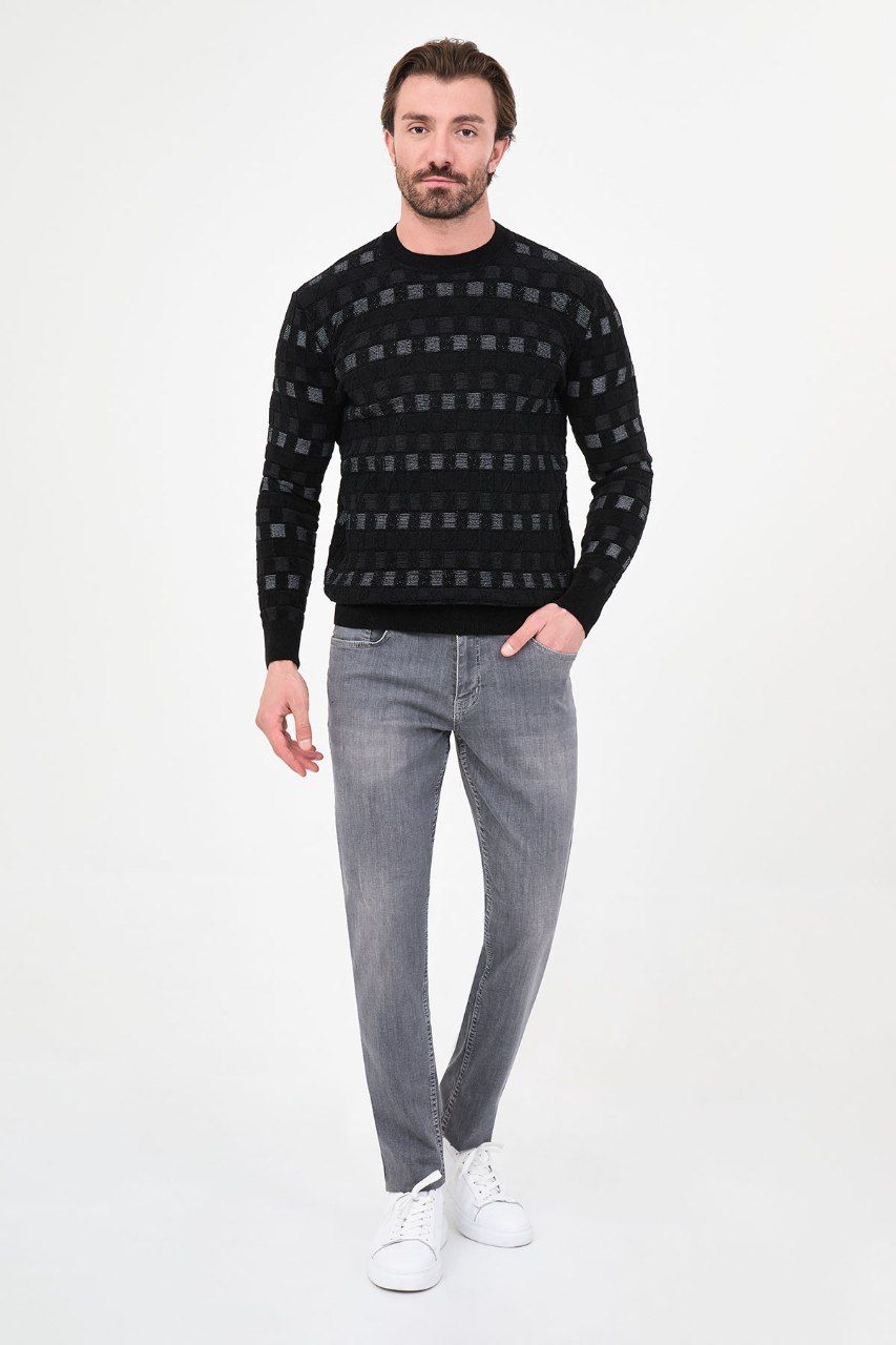 Man wearing a black geometric crew neck sweater with grey trousers