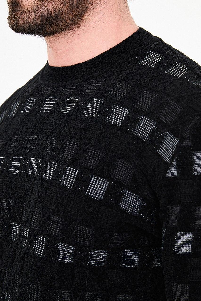 Close-up of square accents and diamond outlines in the black sweater's knit