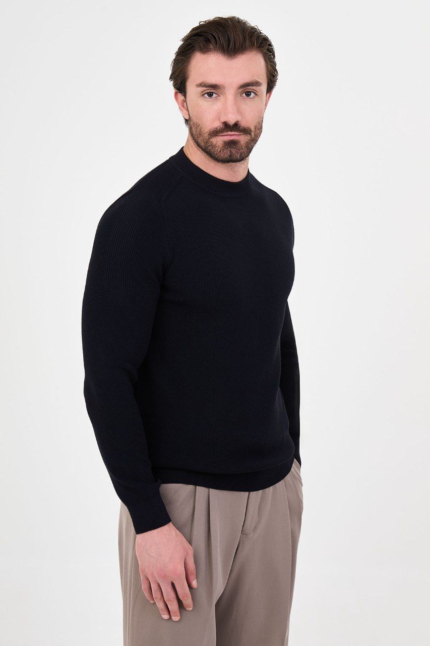 Angled view of a man wearing a black ribbed raglan crew neck sweater