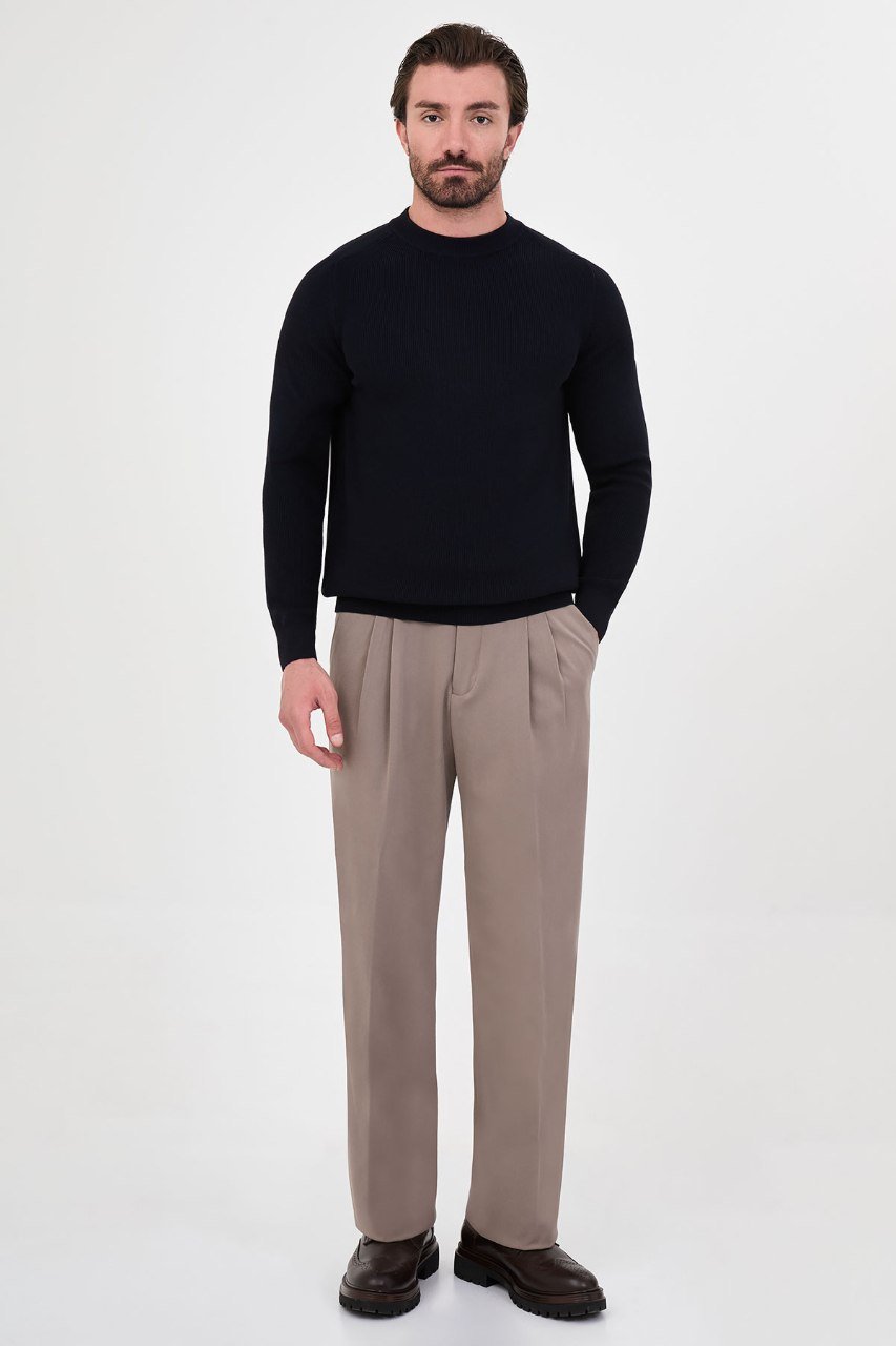 Man wearing a black ribbed raglan crew neck sweater with taupe trousers