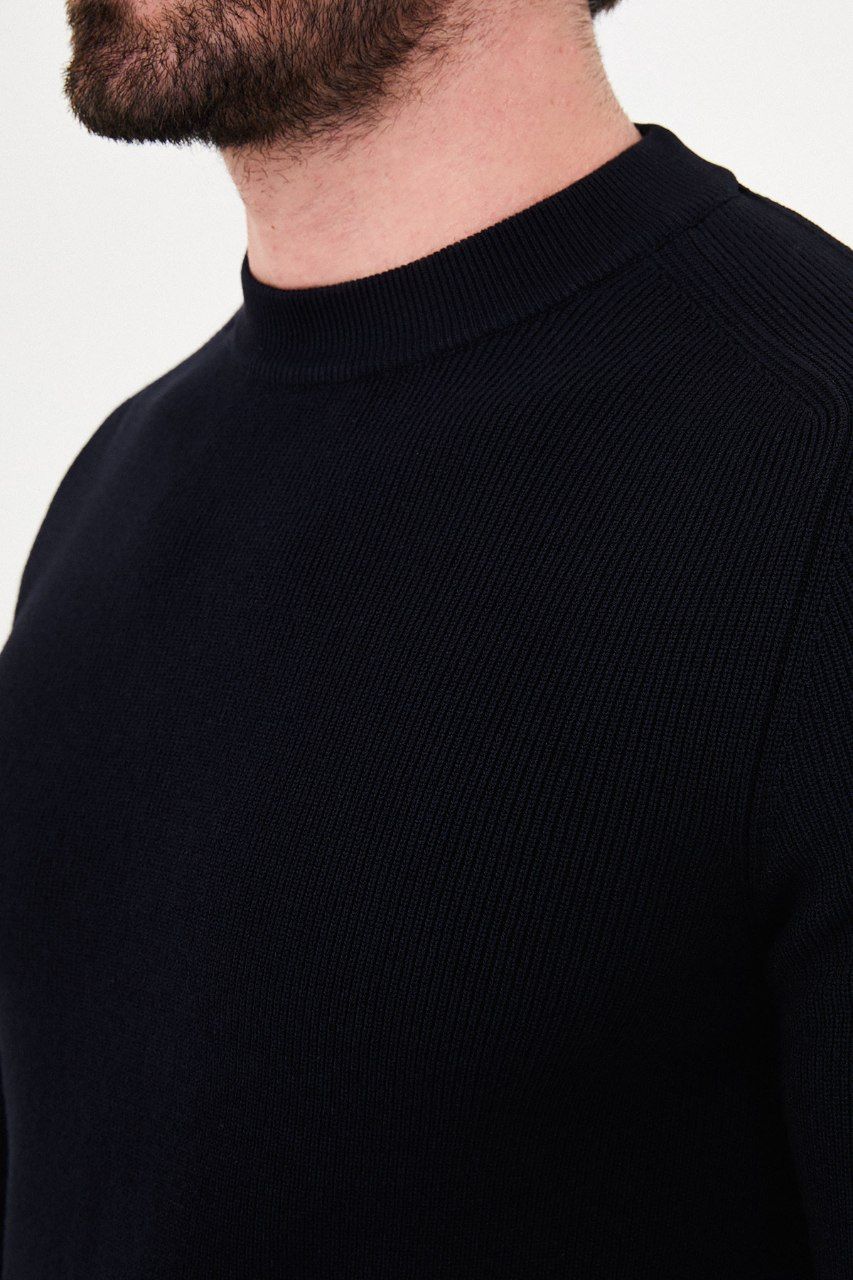 Close-up of the black sweater's fine ribbed knit, crew neckline and raglan seam