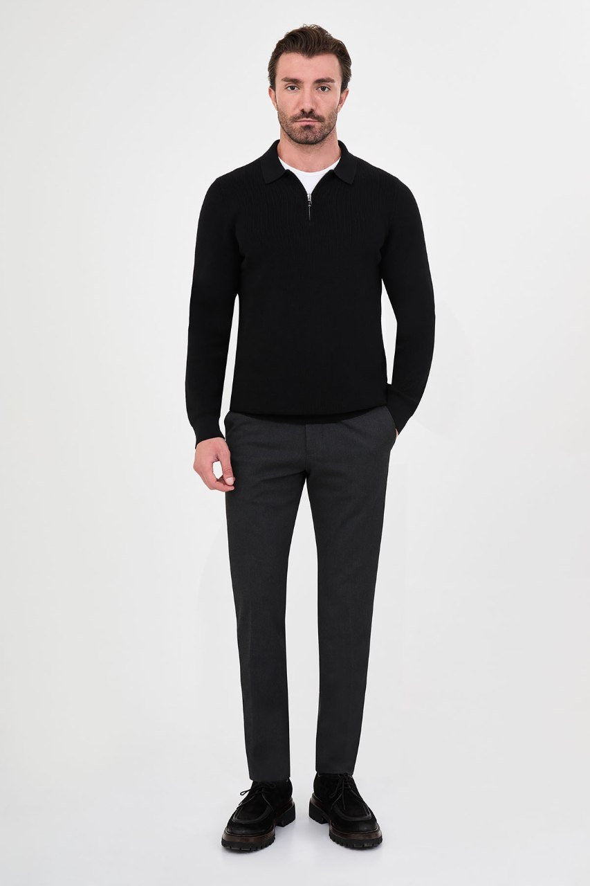 Man wearing a black ribbed zip-polo sweater with grey trousers